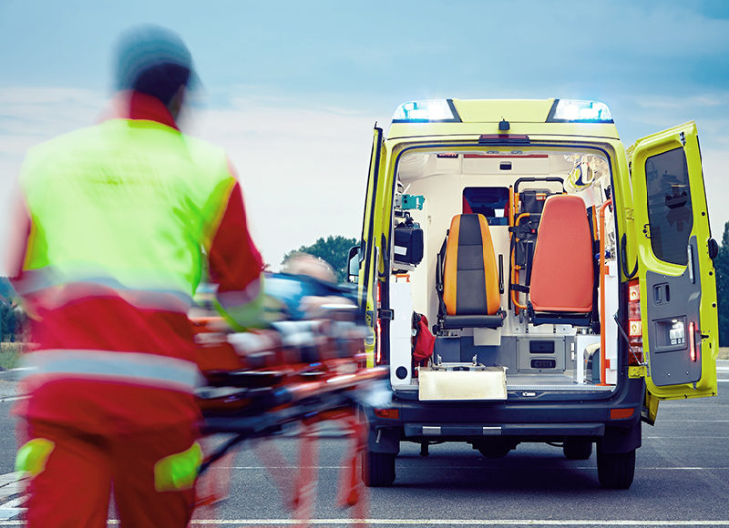 Emergency medical service. Paramedic is pulling stretcher with patient to the ambulance car.