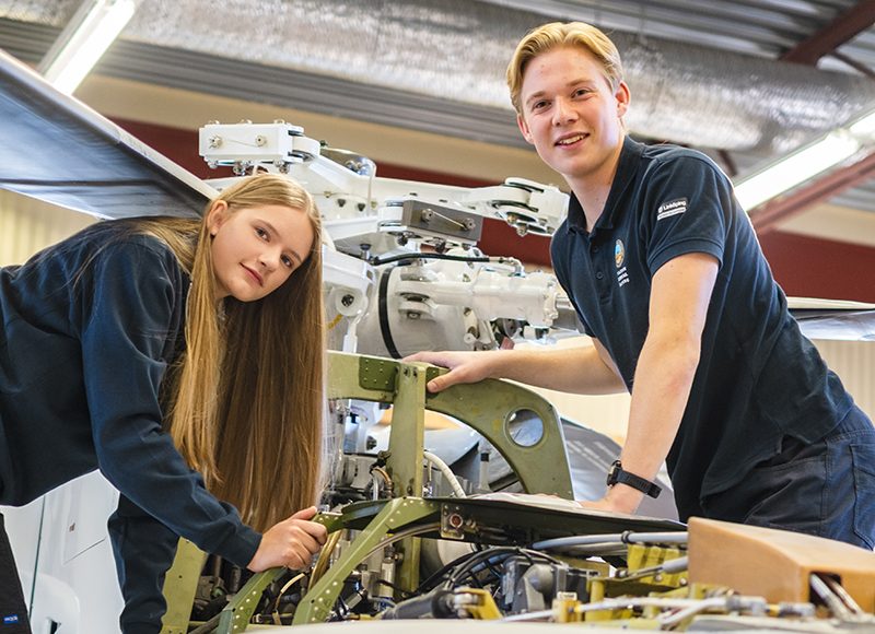 Två gymnasielever mekar med en flygplansmotor.