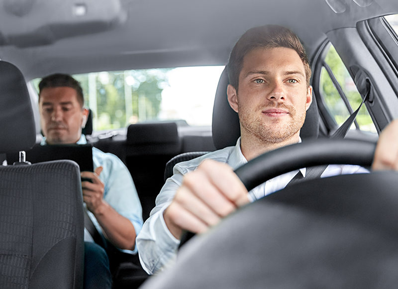 male taxi driver driving car with passenger