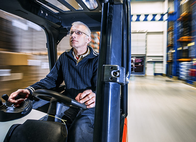 Truckförare kör en truck på ett lager