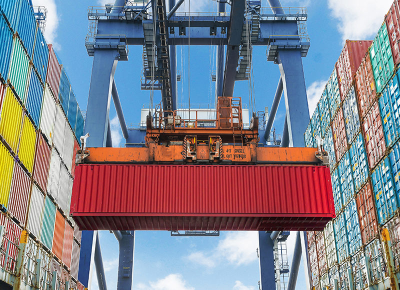 Lindrande lyfter en container i hamnen