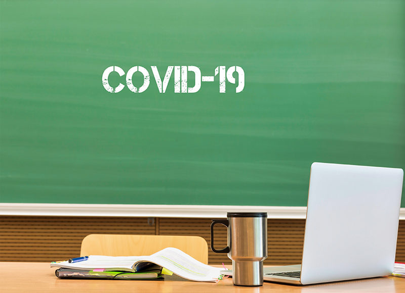 Photo of laptop on professor desk with the text saying Covid 19