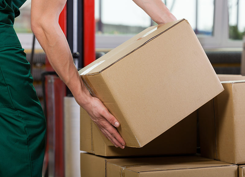 Hands of warehouse worker lifting box