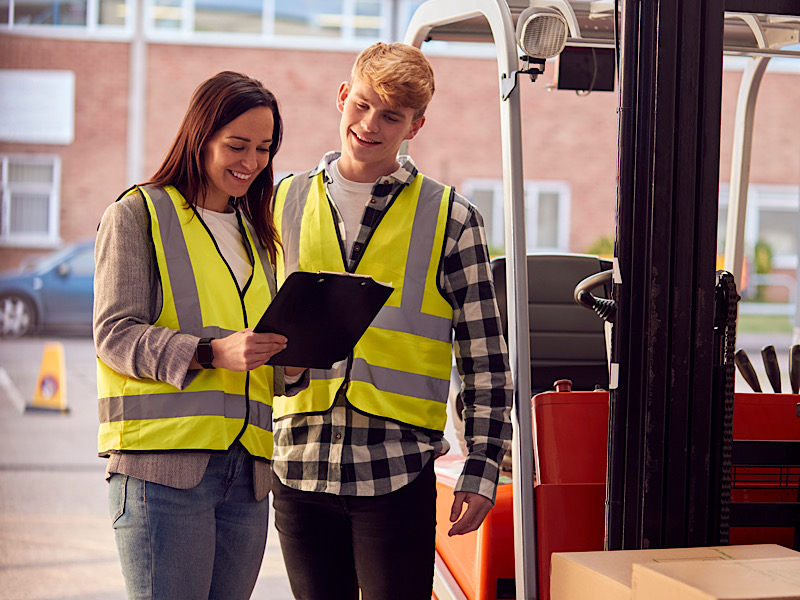 Supervisor Teaching Intern To Operate Fork Lift Truck In Modern Warehouse