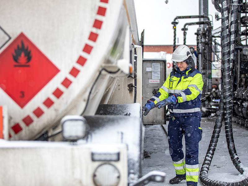 Man som står bredvid tankbil på depå