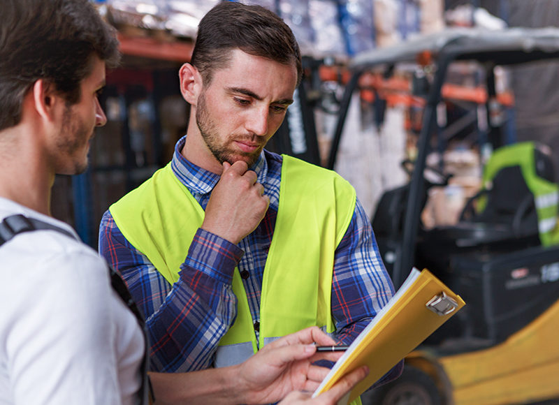 Workers discussing something and standing in warehouse.